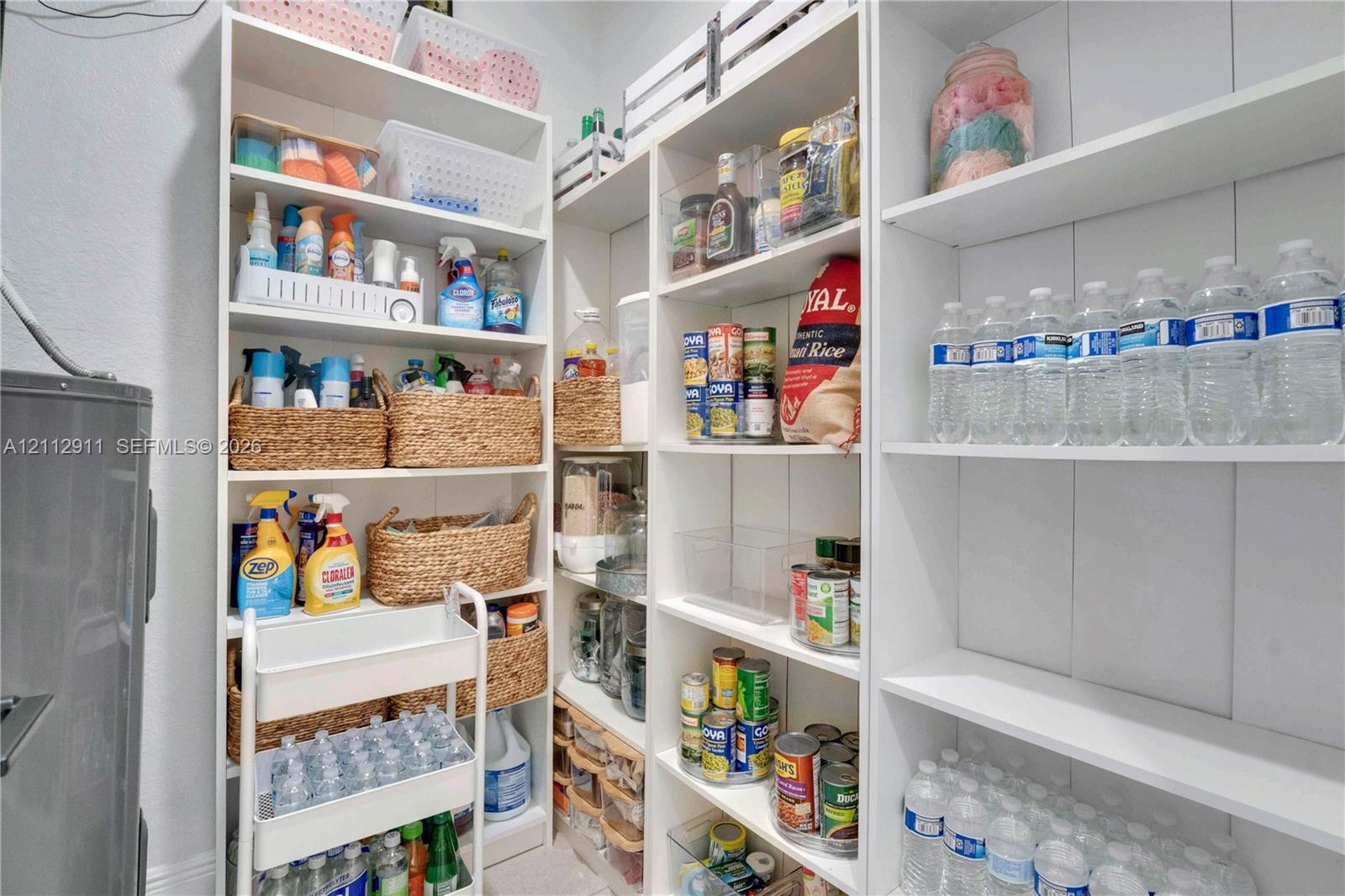 Built-in white floor-to-ceiling cabinetry with multi-level adjustable shelving and vertical plank-style wall paneling