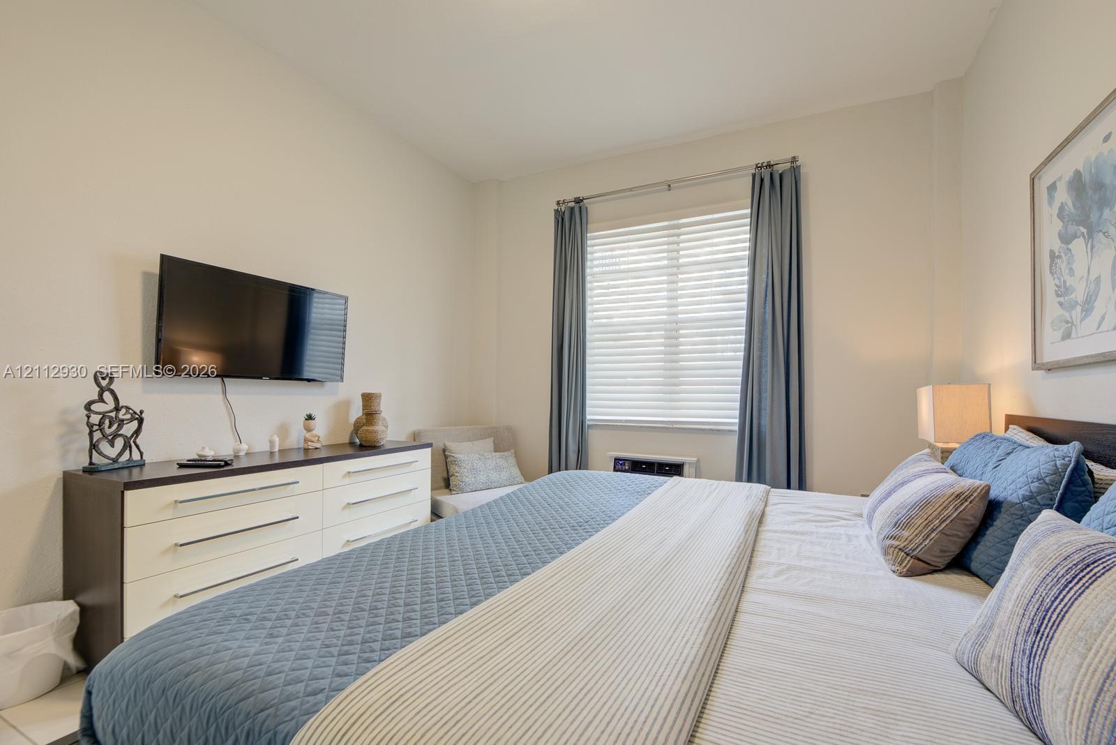 Neutral walls, multi-pane window with horizontal blinds, and window drapery hardware