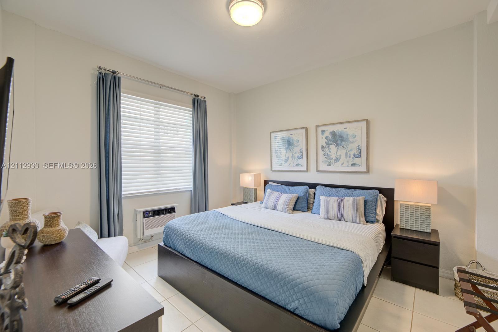 Neutral-toned room featuring large-format tile flooring, a recessed ceiling light fixture, and a wall-mounted window air conditioning unit