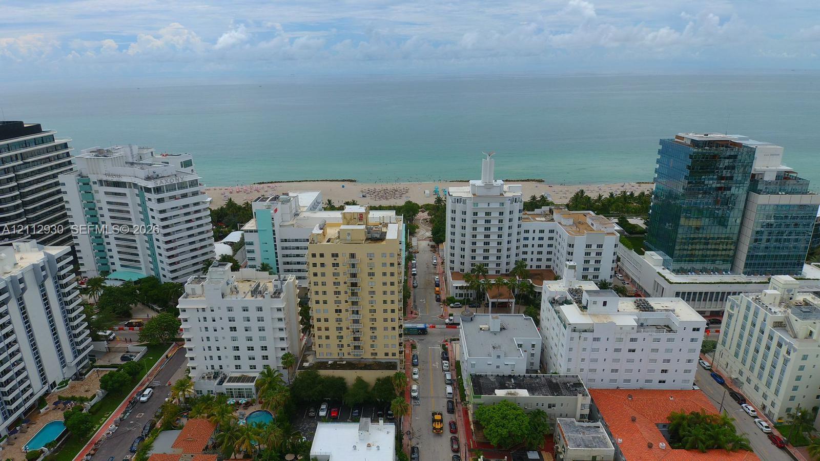 Aerial perspective of an urban coastal setting featuring high-rise architecture and direct oceanfront access to the beach