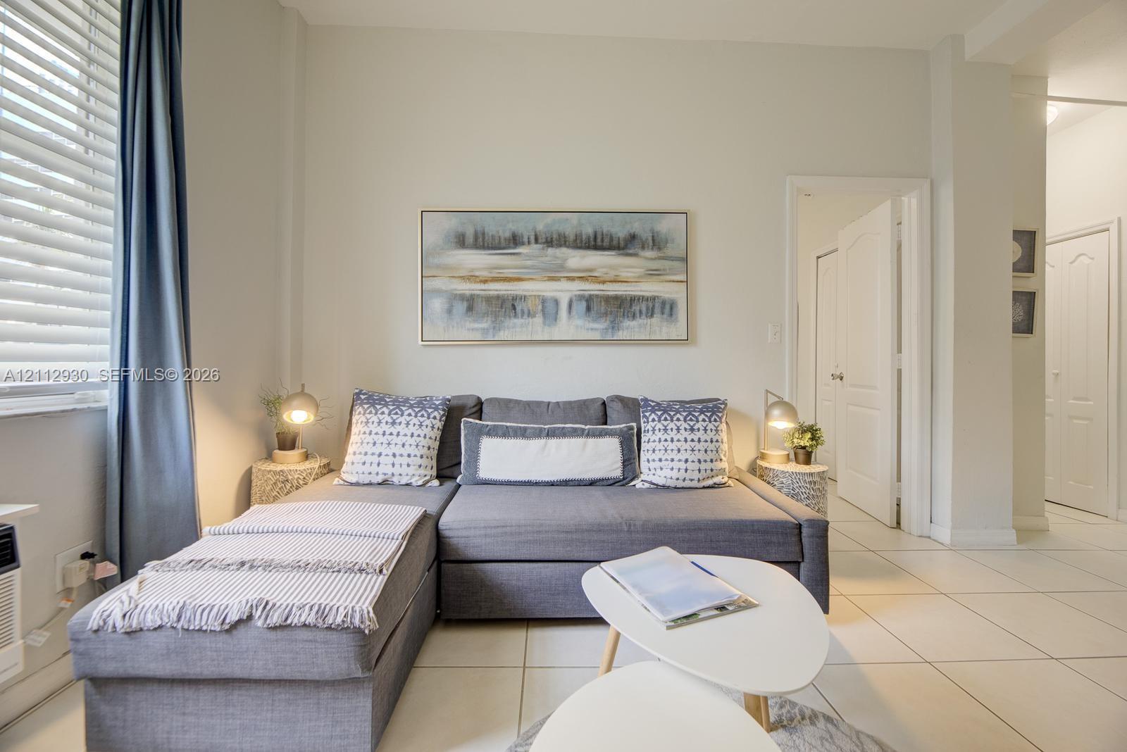 Interior space featuring large-format tile flooring, horizontal slat window blinds, and paneled interior doors
