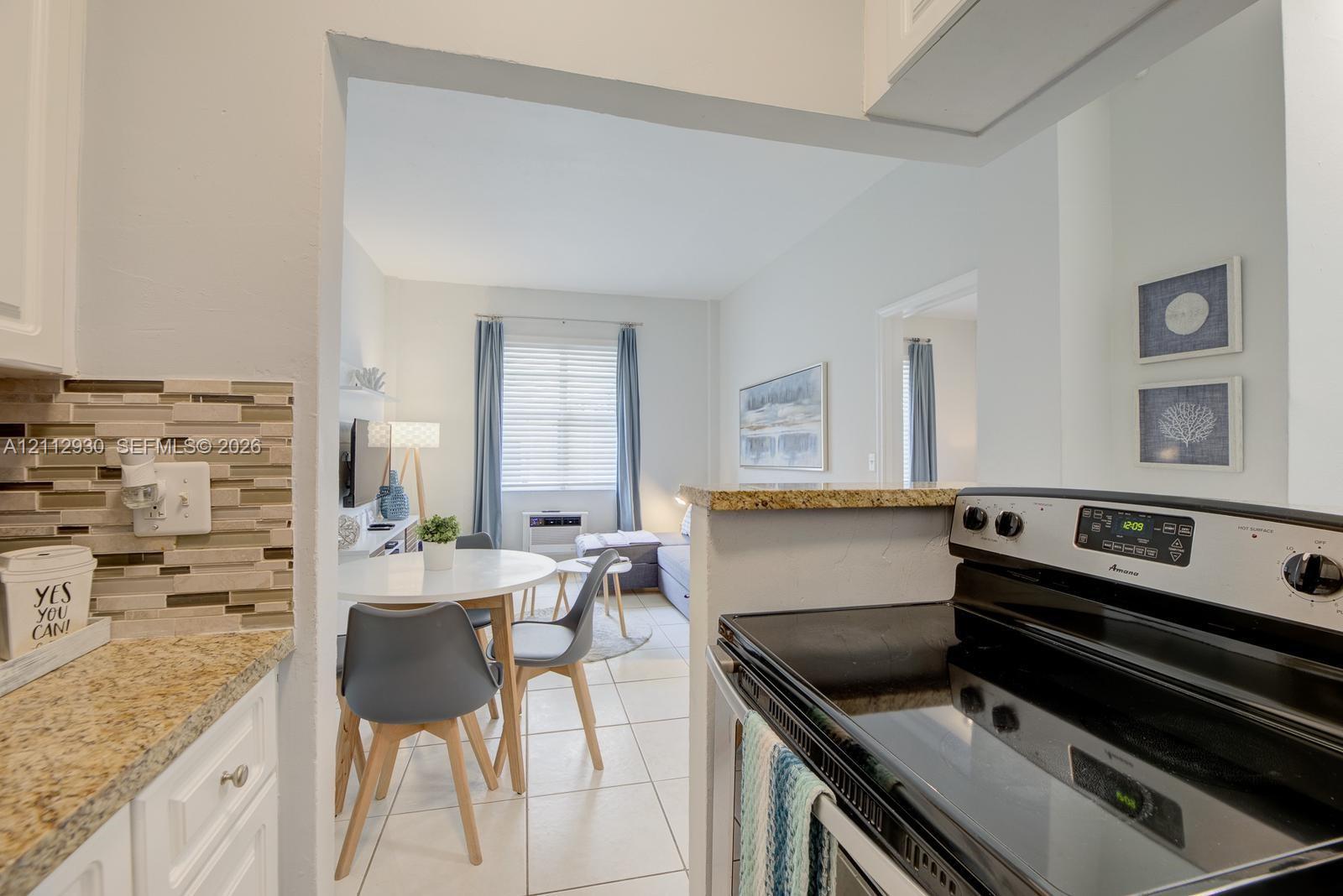 Kitchen featuring stone-finish countertops, tile flooring, and a multi-toned glass tile backsplash