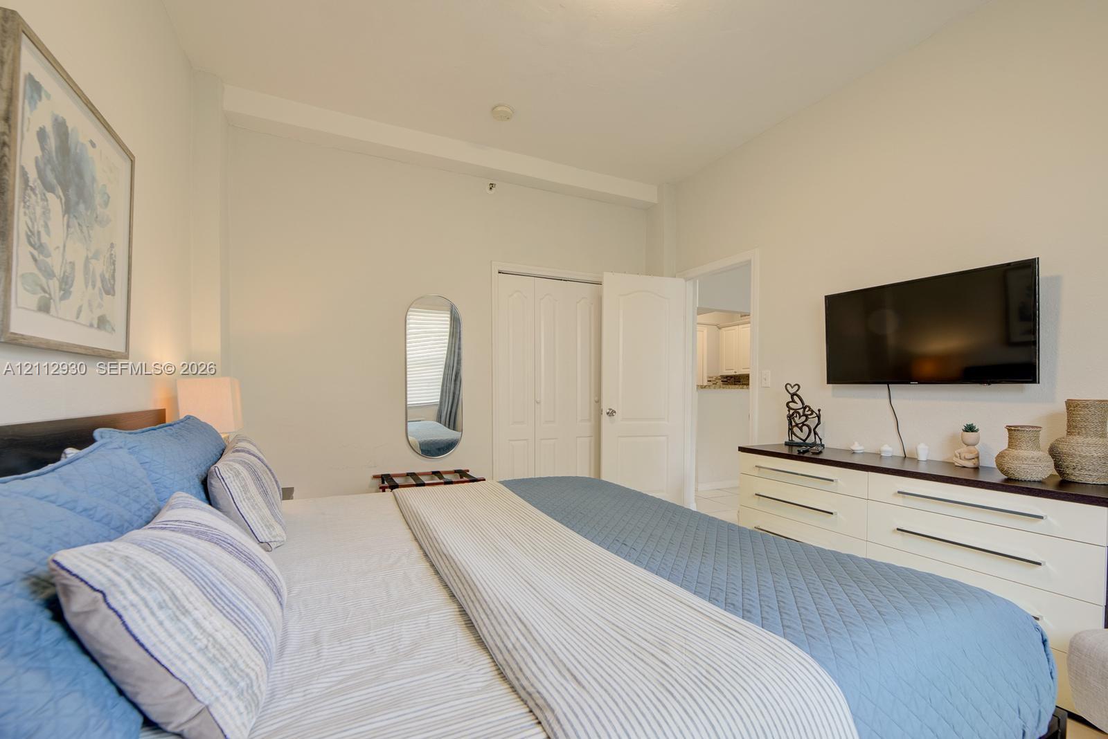 Neutral-toned interior featuring high ceilings, a reach-in closet with double-panel doors, and a wall-mounted television