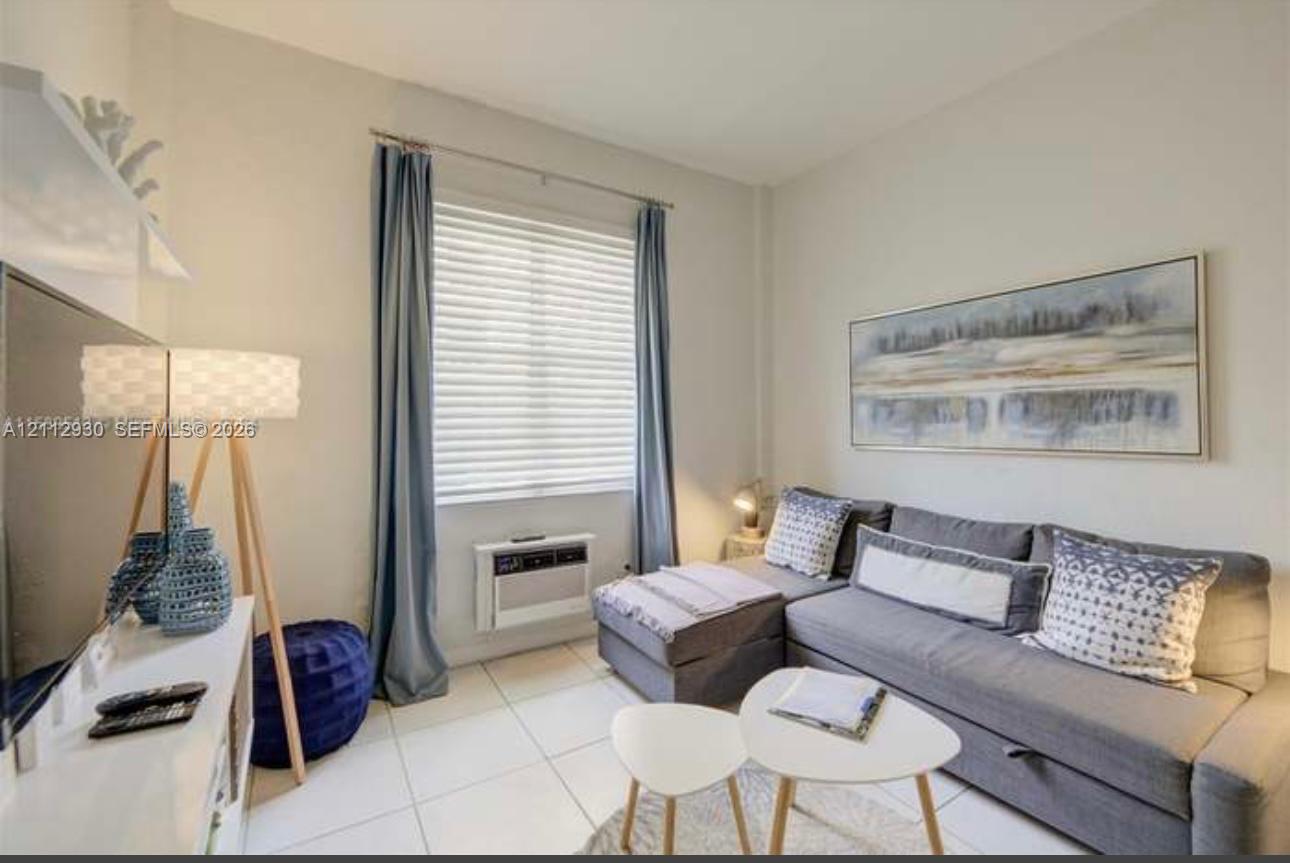 Neutral-toned walls paired with large-format light tile flooring and a wall-mounted climate control unit