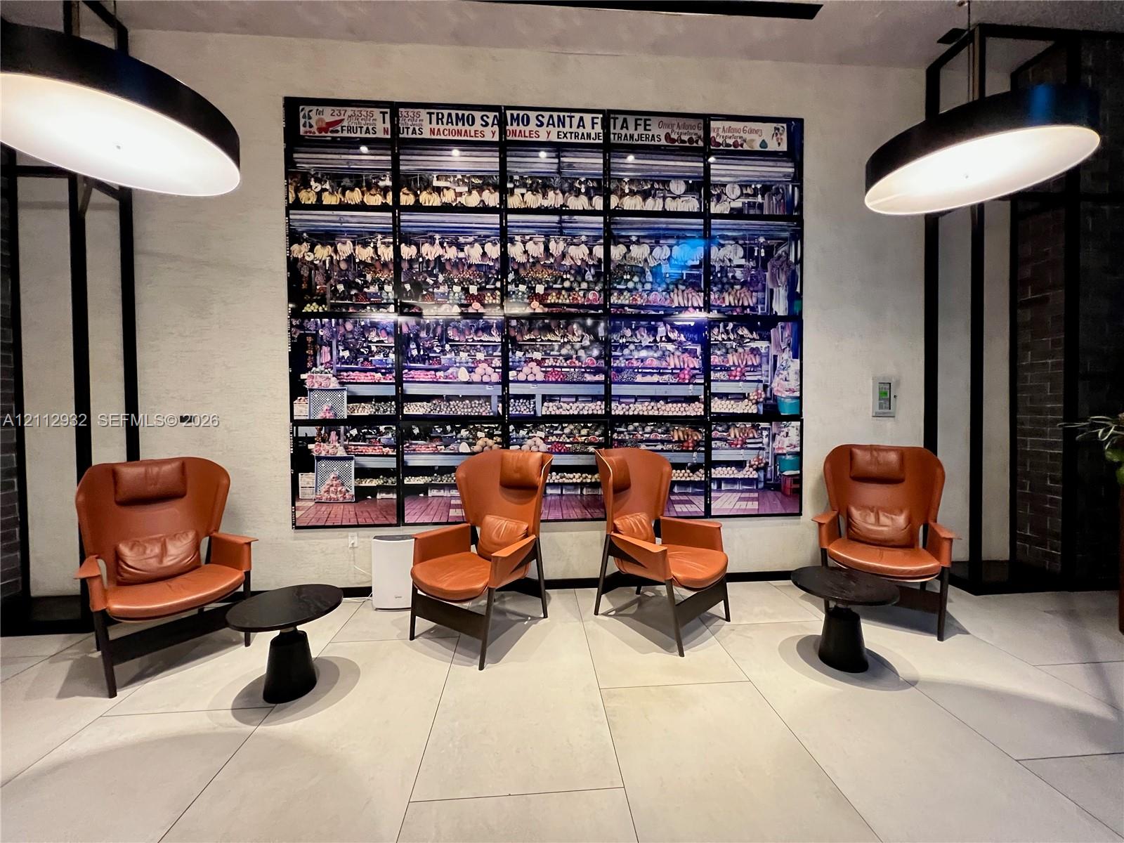 Large-format decorative wall installation, oversized circular pendant lighting, and light-toned tile flooring
