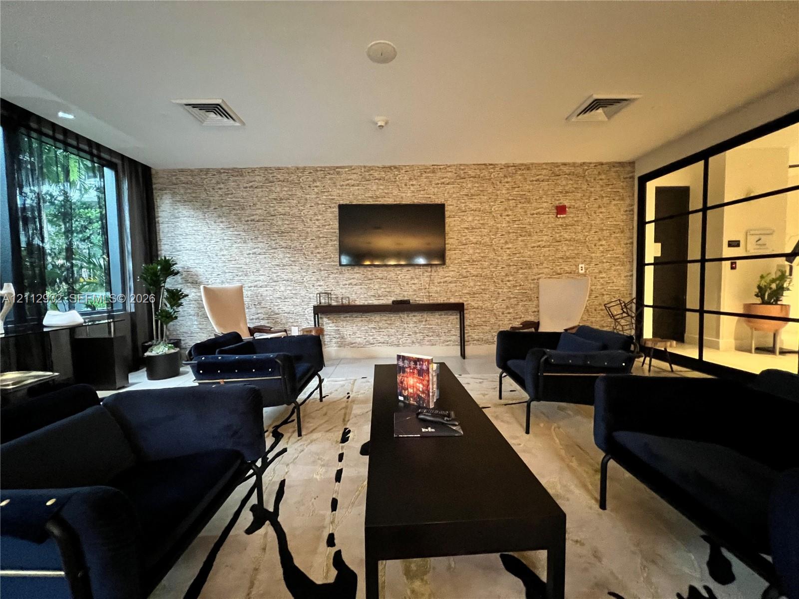 Textured stone-finish accent wall, floor-to-ceiling windows, and industrial-style metal-framed glass partition
