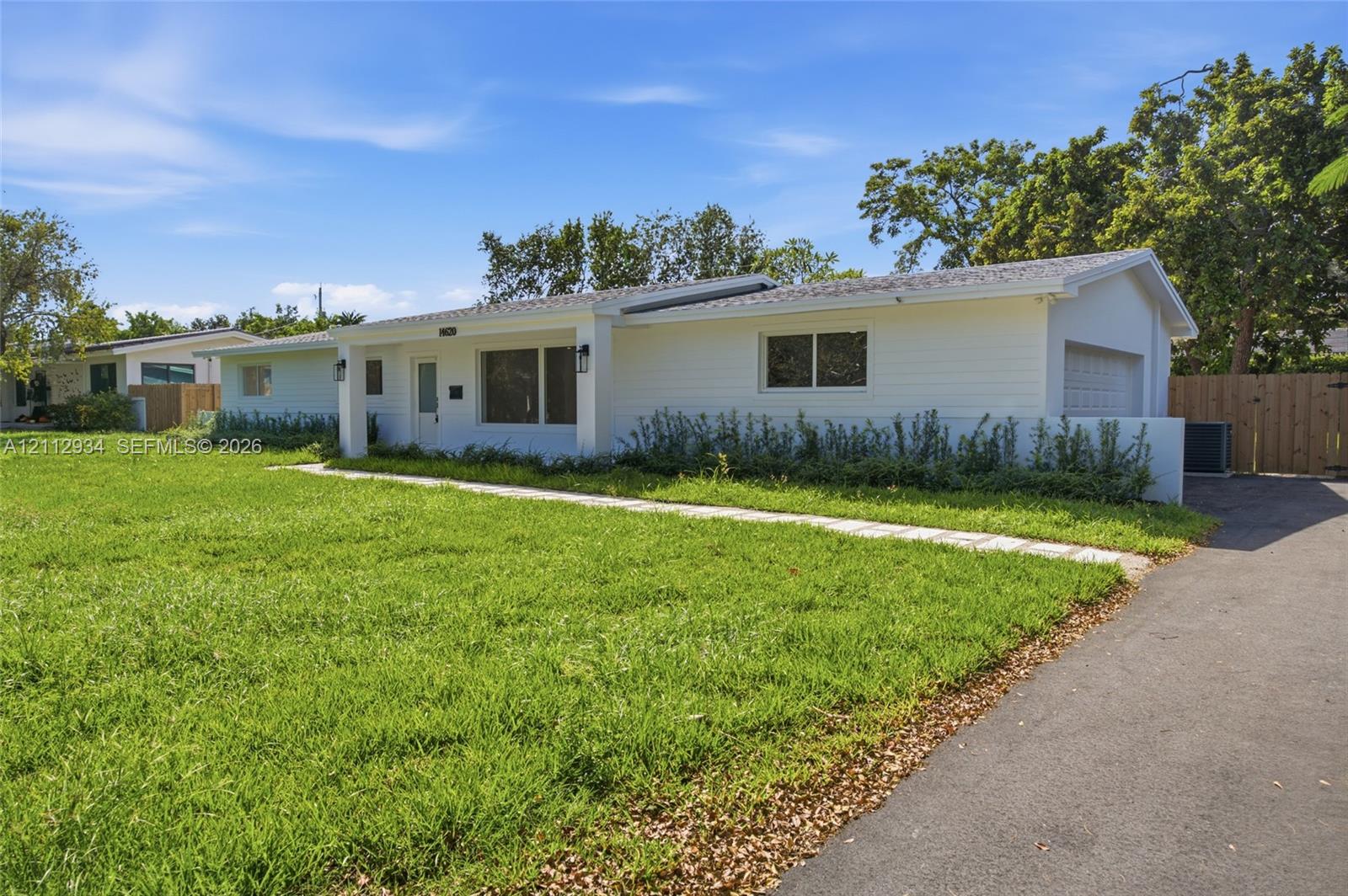 Single-story exterior featuring white horizontal siding, a covered entryway, an attached garage, and a paved driveway