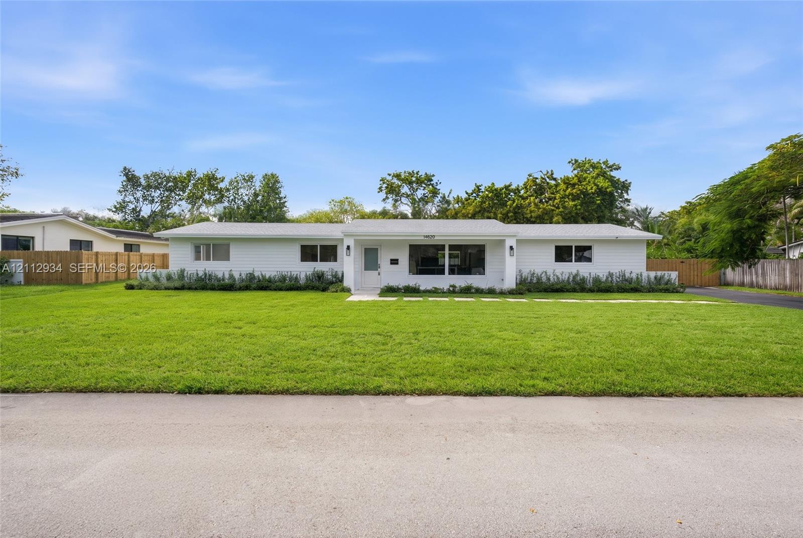 Single-story ranch-style exterior featuring white horizontal siding, a covered entryway, rectangular windows, and a paved walkway