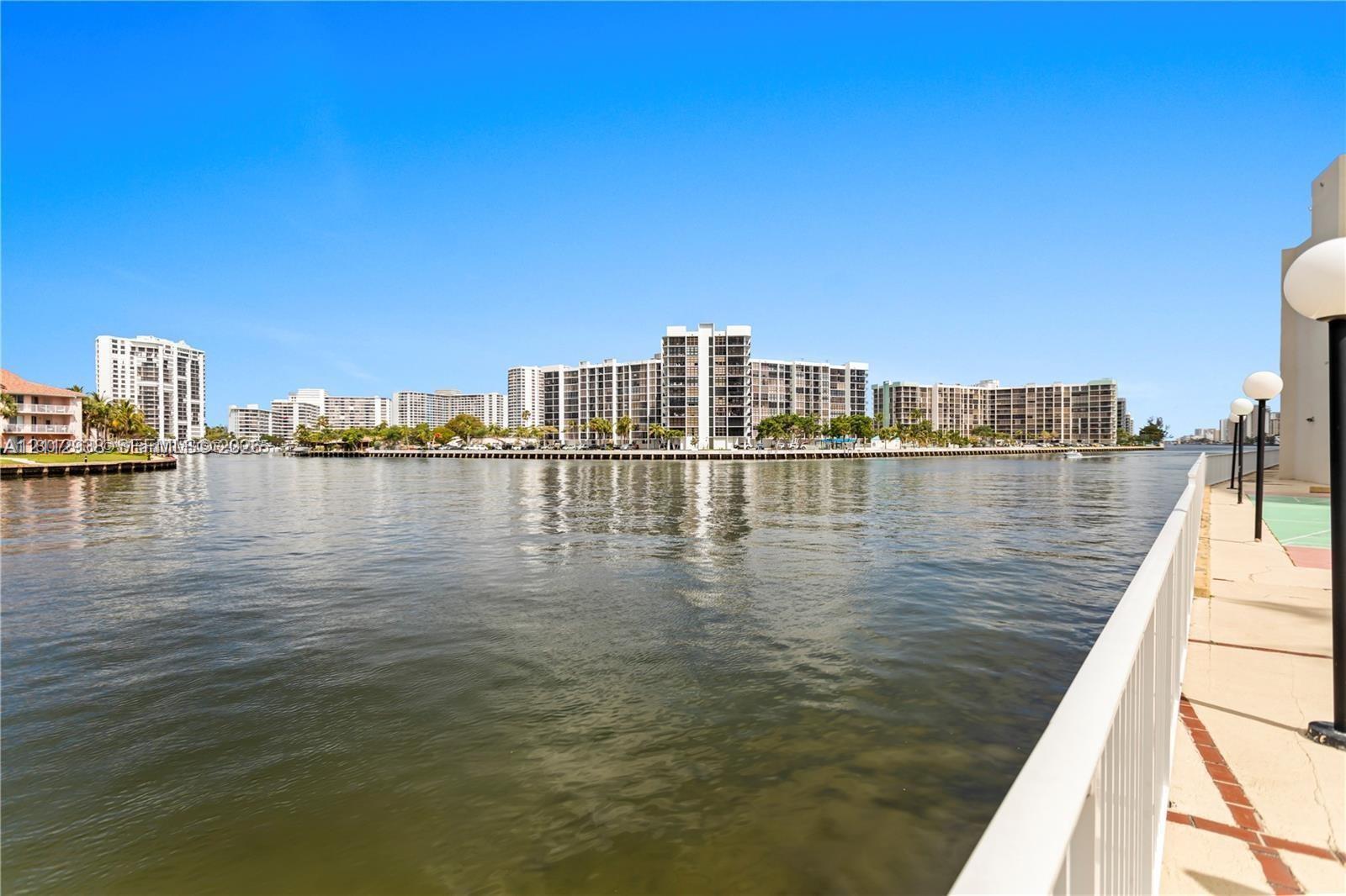 Waterfront concrete promenade featuring a white metal safety railing and decorative globe-style post lighting