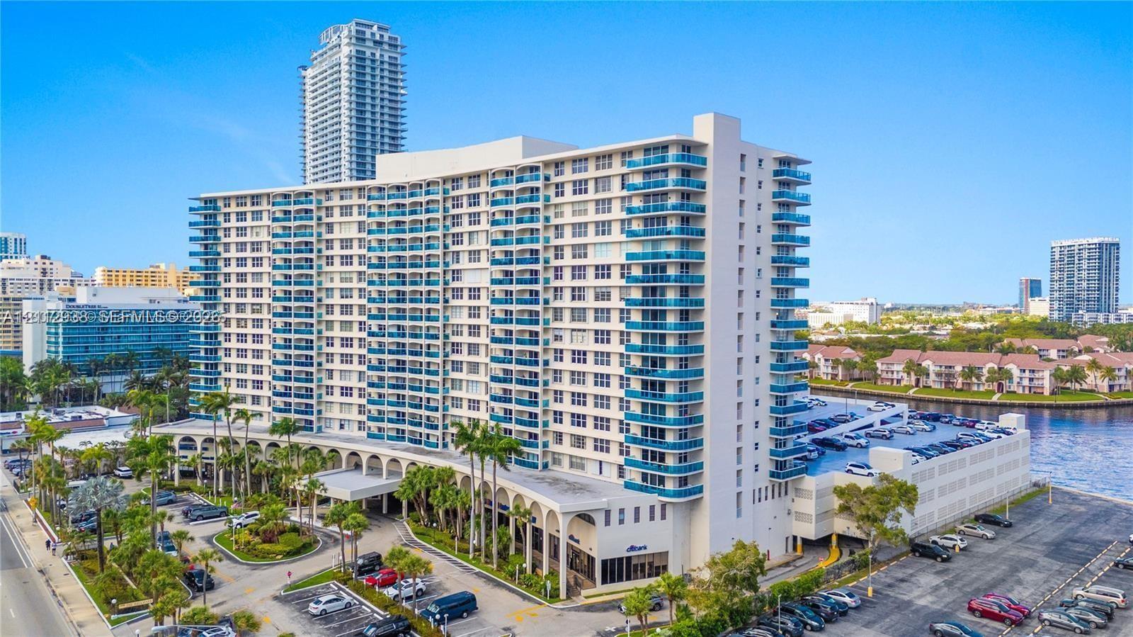 High-rise residential building featuring stacked balconies, exterior archways, on-site parking, and water frontage