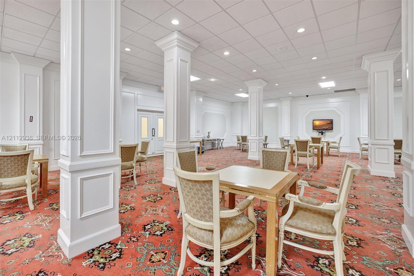 Spacious open-concept interior featuring decorative columns, recessed lighting, patterned carpeting, and recessed wall paneling