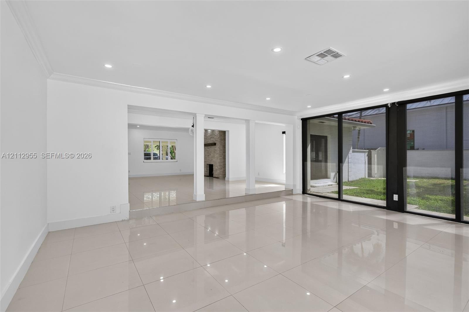 Polished tile flooring, recessed lighting, expansive sliding glass doors, and structural pillars featuring a raised elevation