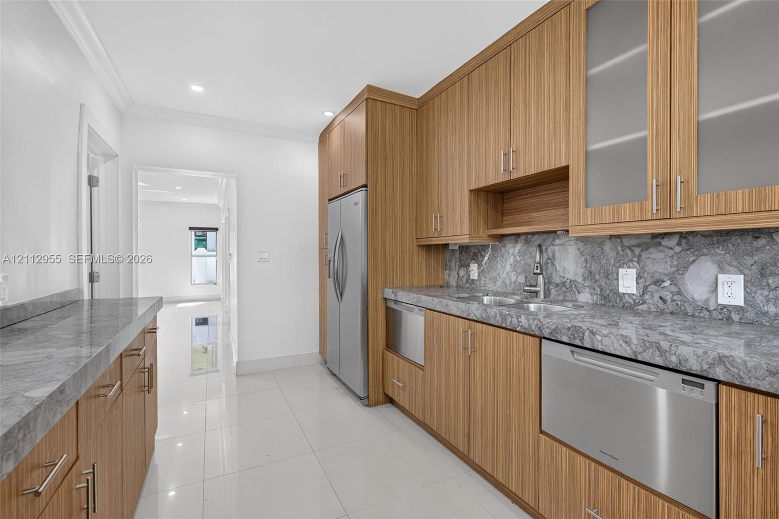 Wood-finish cabinetry featuring glass-front upper cabinets, stainless steel appliances, stone-surface countertops, and high-gloss tile flooring