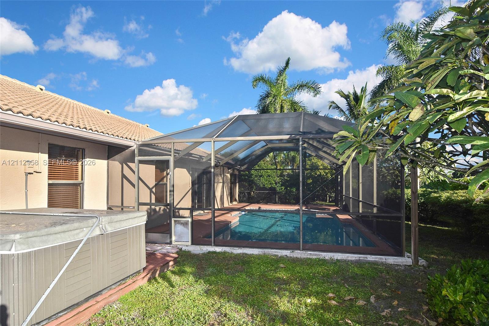 Screened-in pool enclosure featuring a concrete deck and an exterior spa