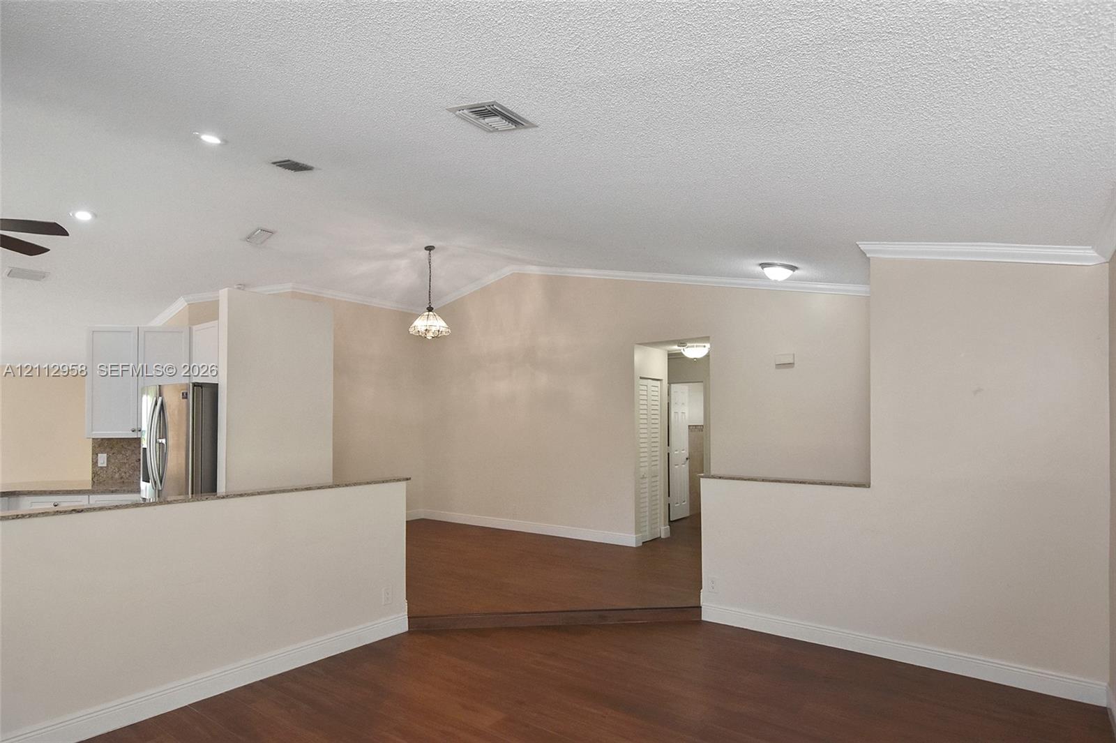 Vaulted ceilings, wood-finish flooring, recessed lighting, and partial height partition walls with stone-surface counters