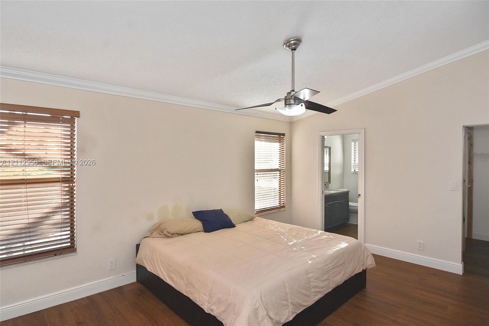 Vaulted ceiling with a central brushed-nickel ceiling fan, wood-finish flooring, and horizontal window blinds