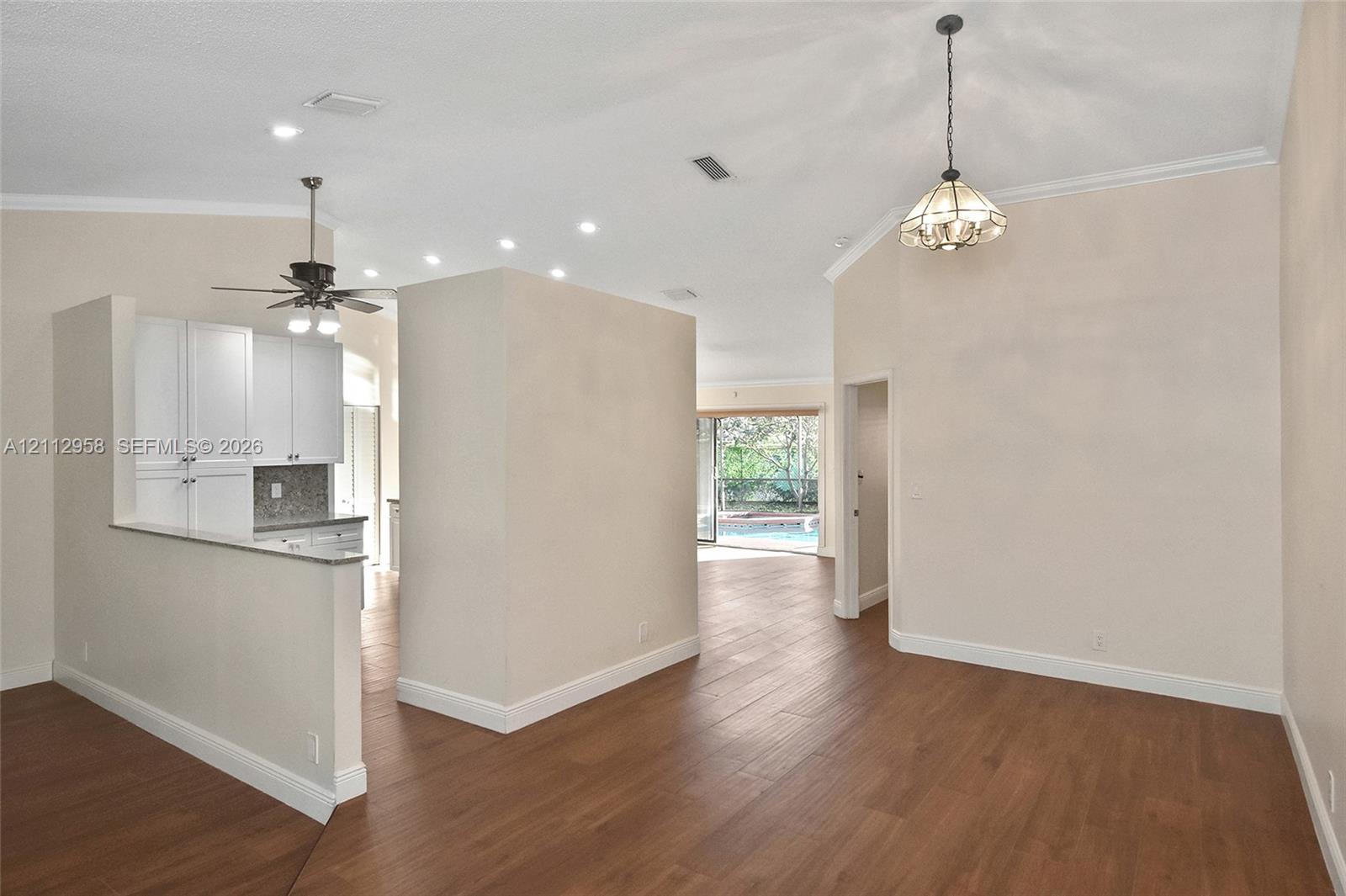 Vaulted ceilings featuring recessed lighting, wood-finish flooring, white cabinetry, and multi-light fixtures