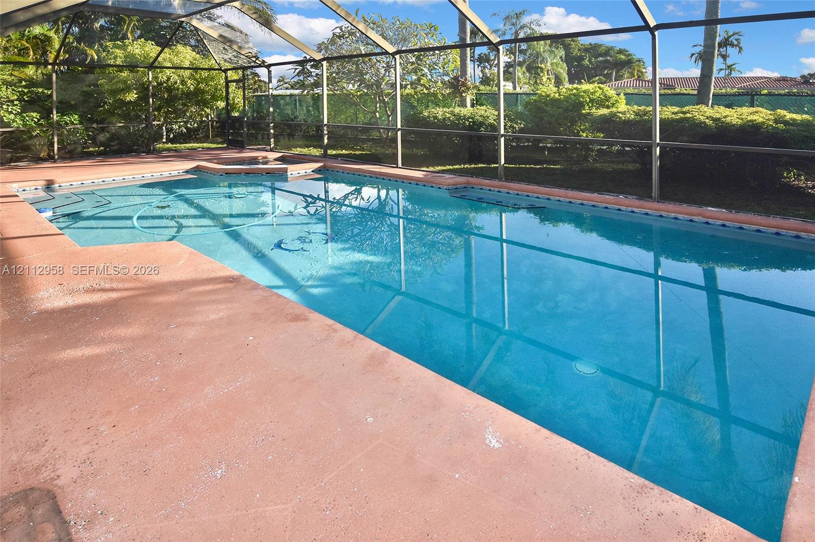 In-ground swimming pool enclosed by a screen structure with a concrete deck and perimeter landscaping