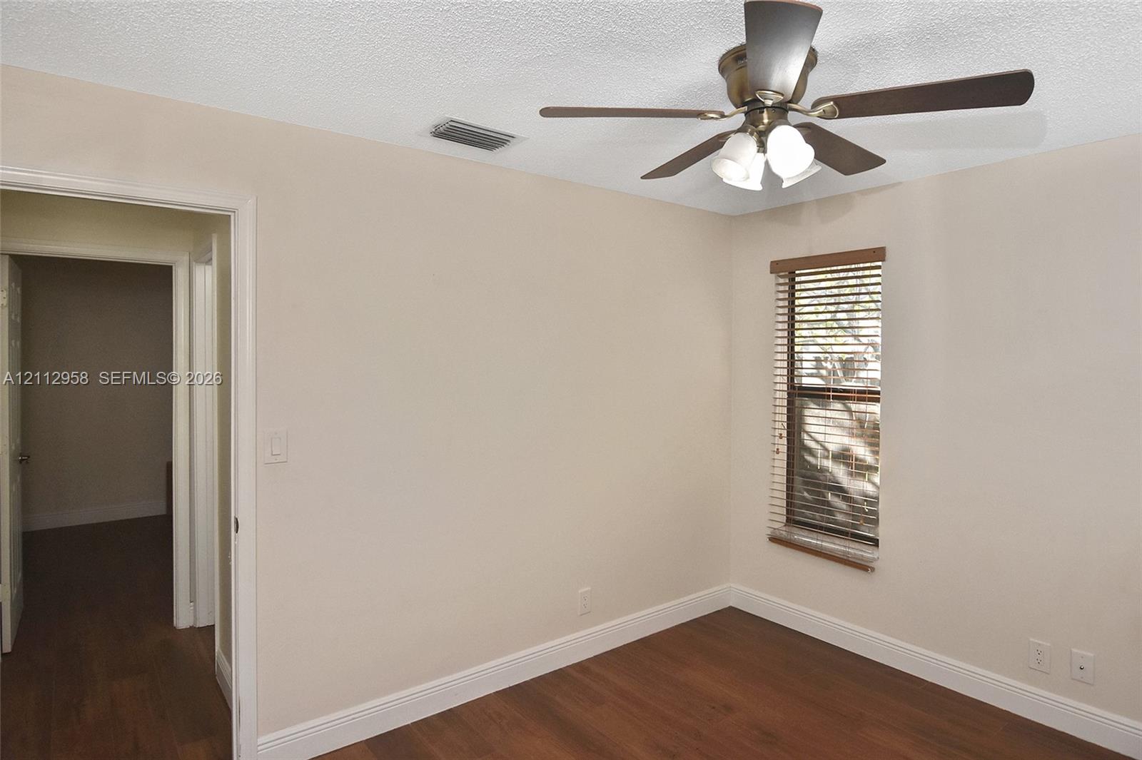 Wood-finish flooring, ceiling fan with integrated lighting, and horizontal window blinds