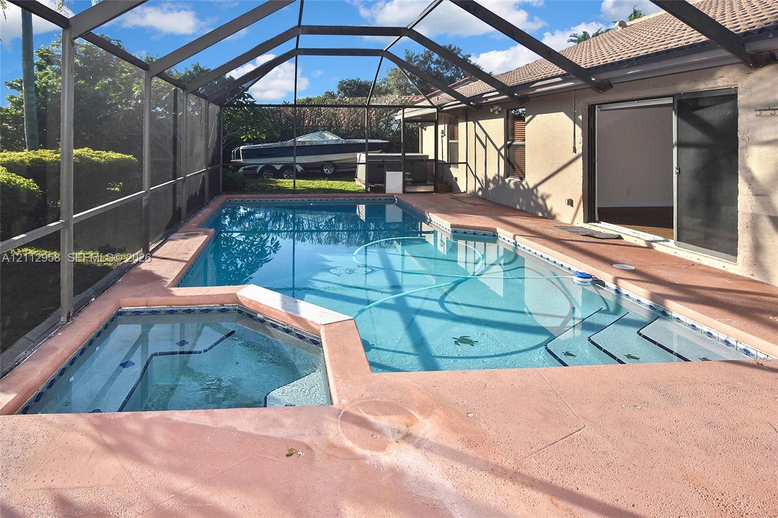Screened-in patio featuring a swimming pool, integrated spa, and concrete deck