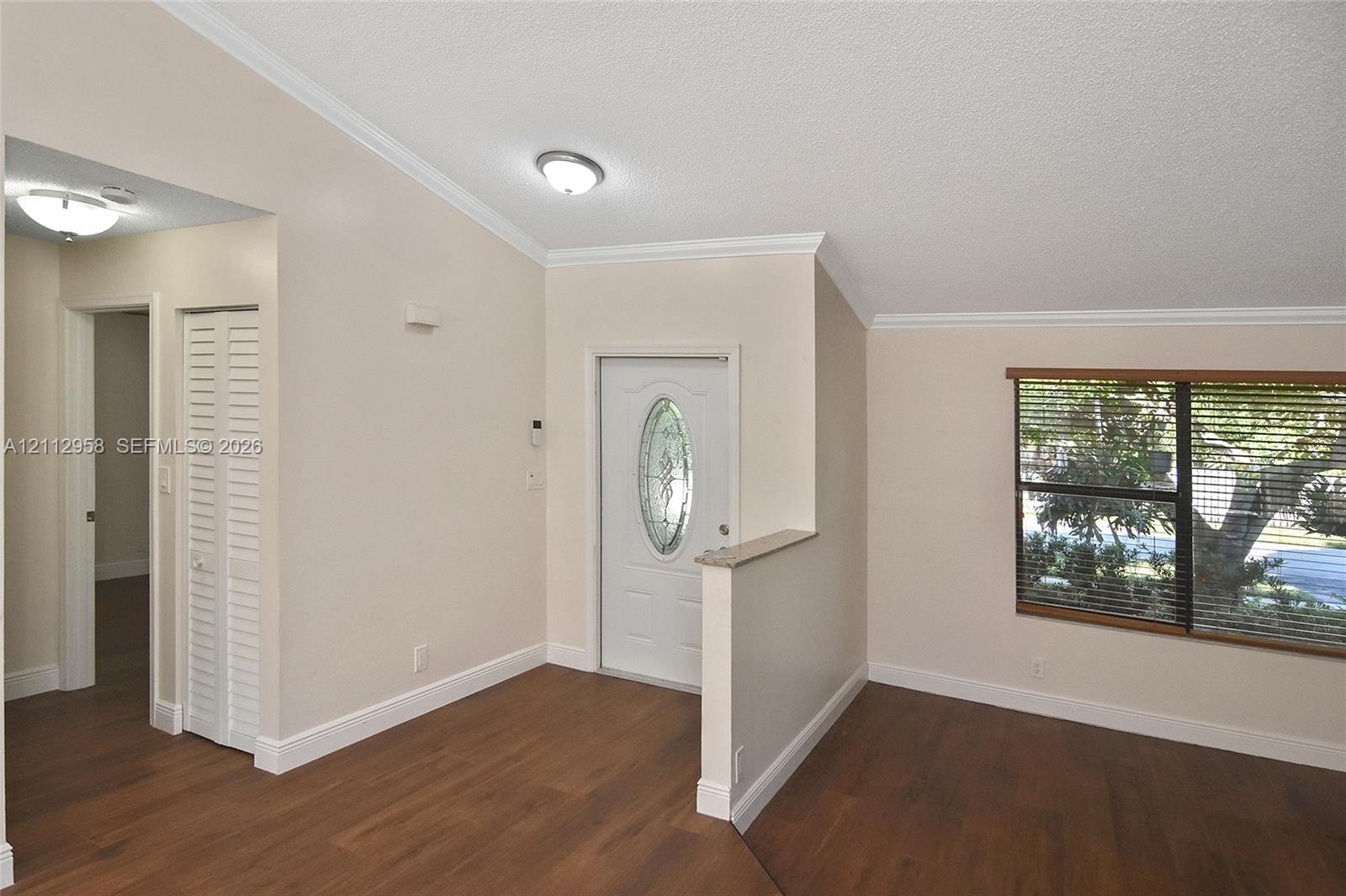 Vaulted ceilings, wood-finish flooring, half-wall partition, louvered closet door, and an exterior door with an oval glass insert