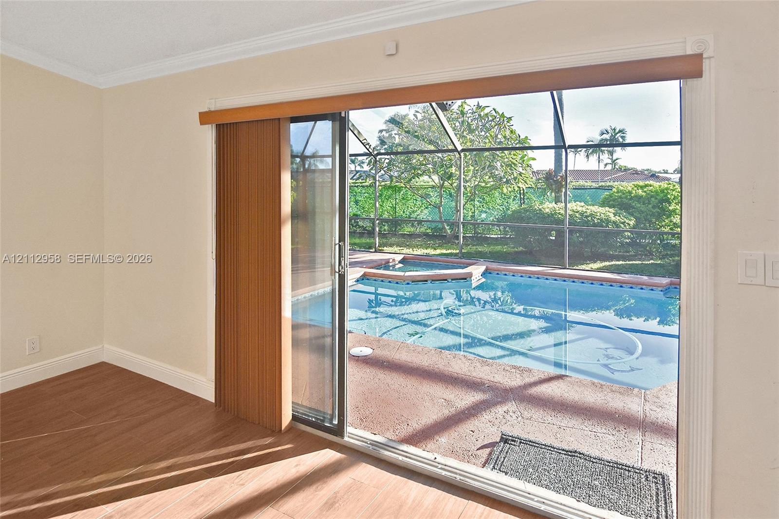 Sliding glass door opening to a screened-in patio featuring a swimming pool, spa, and tile flooring
