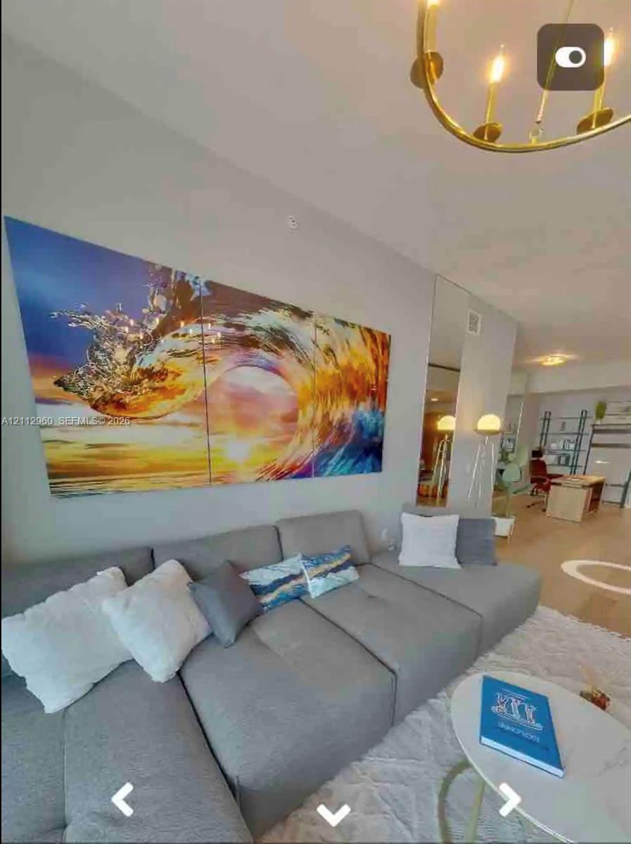 Circular gold-tone chandelier with multi-bulb fixtures and floor-to-ceiling mirror paneling