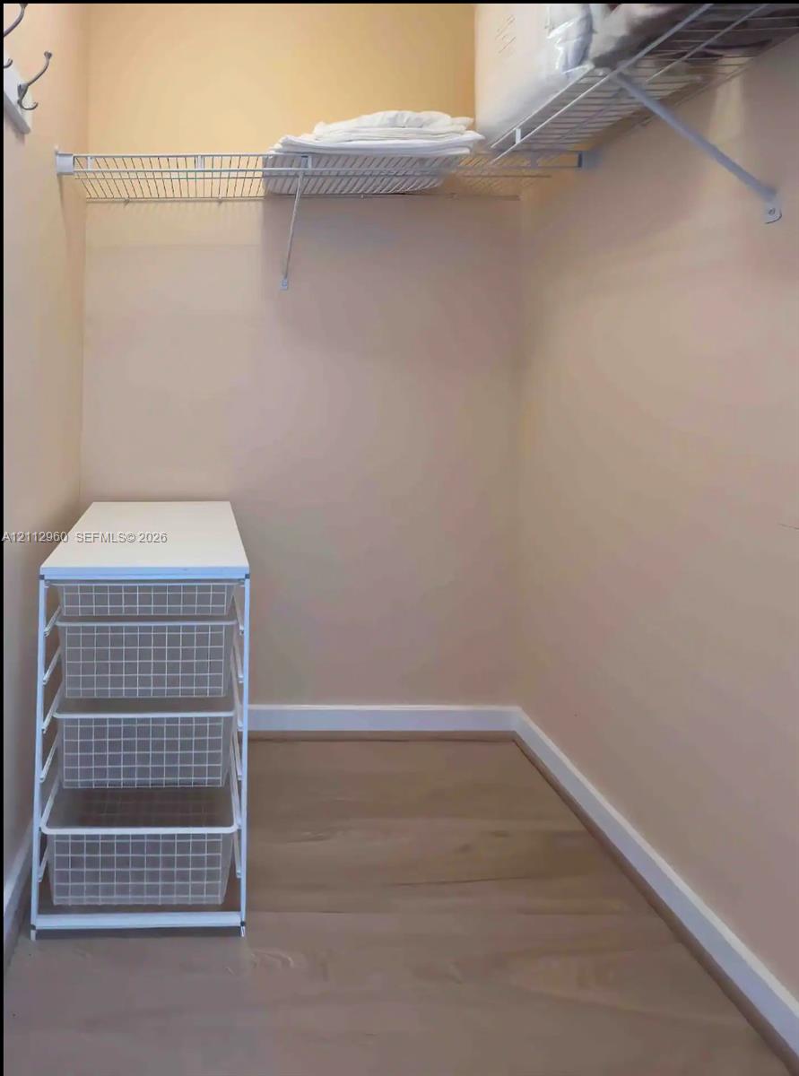 Storage area featuring wood-finish flooring, metal wire shelving, and a white built-in multi-drawer organization unit
