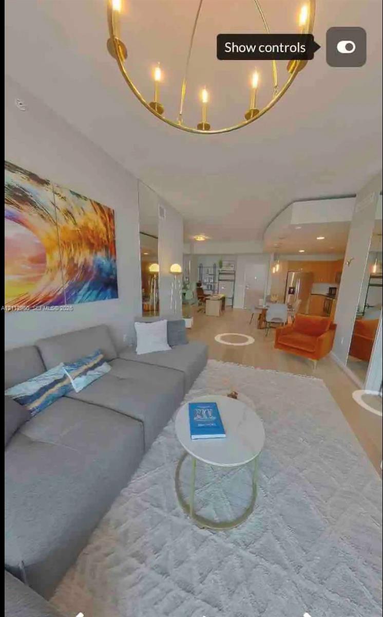 Open-concept space featuring light wood-finish flooring, a metallic circular chandelier, full-height wall mirrors, and recessed lighting