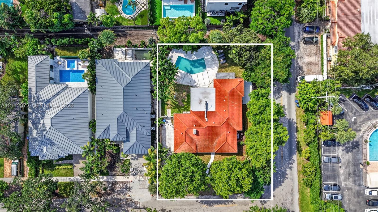 Aerial perspective featuring a terracotta tile roof, private swimming pool, concrete patio, and mature tree canopy on the parcel