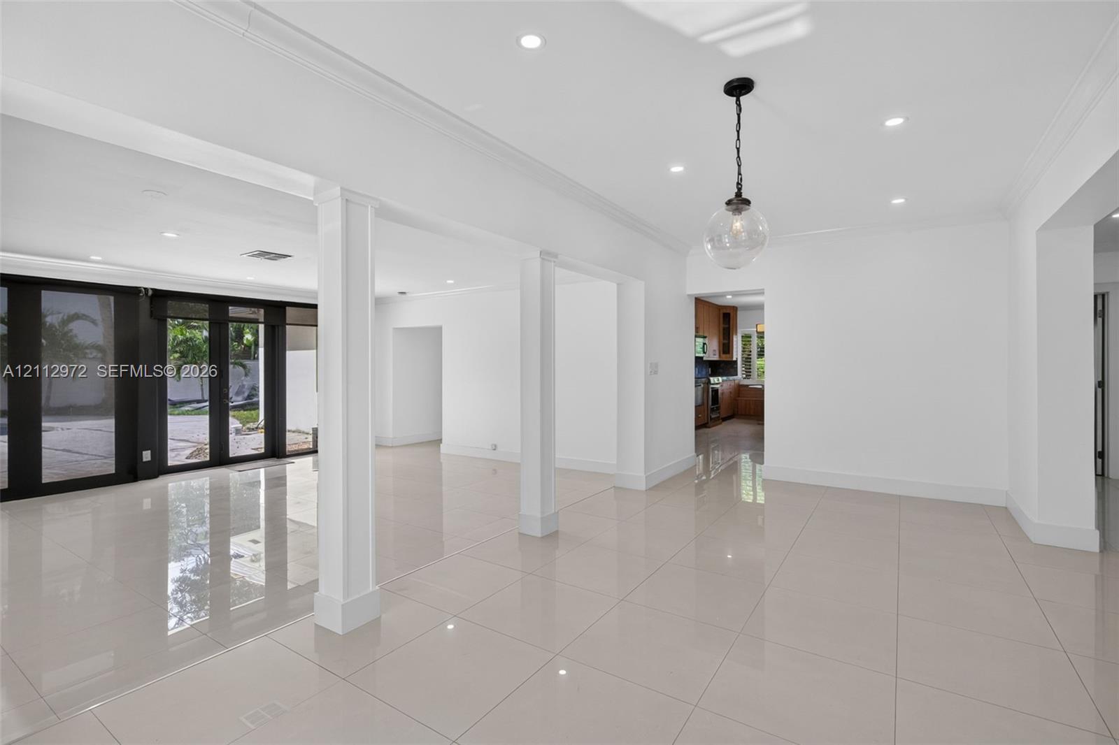 Open-concept interior featuring large-format polished tile flooring, recessed lighting, architectural columns, and dark-framed glass paneled doors Open-concept interior featuring large-format polished tile flooring, recessed lighting, architectural columns, and dark-framed glass paneled doors