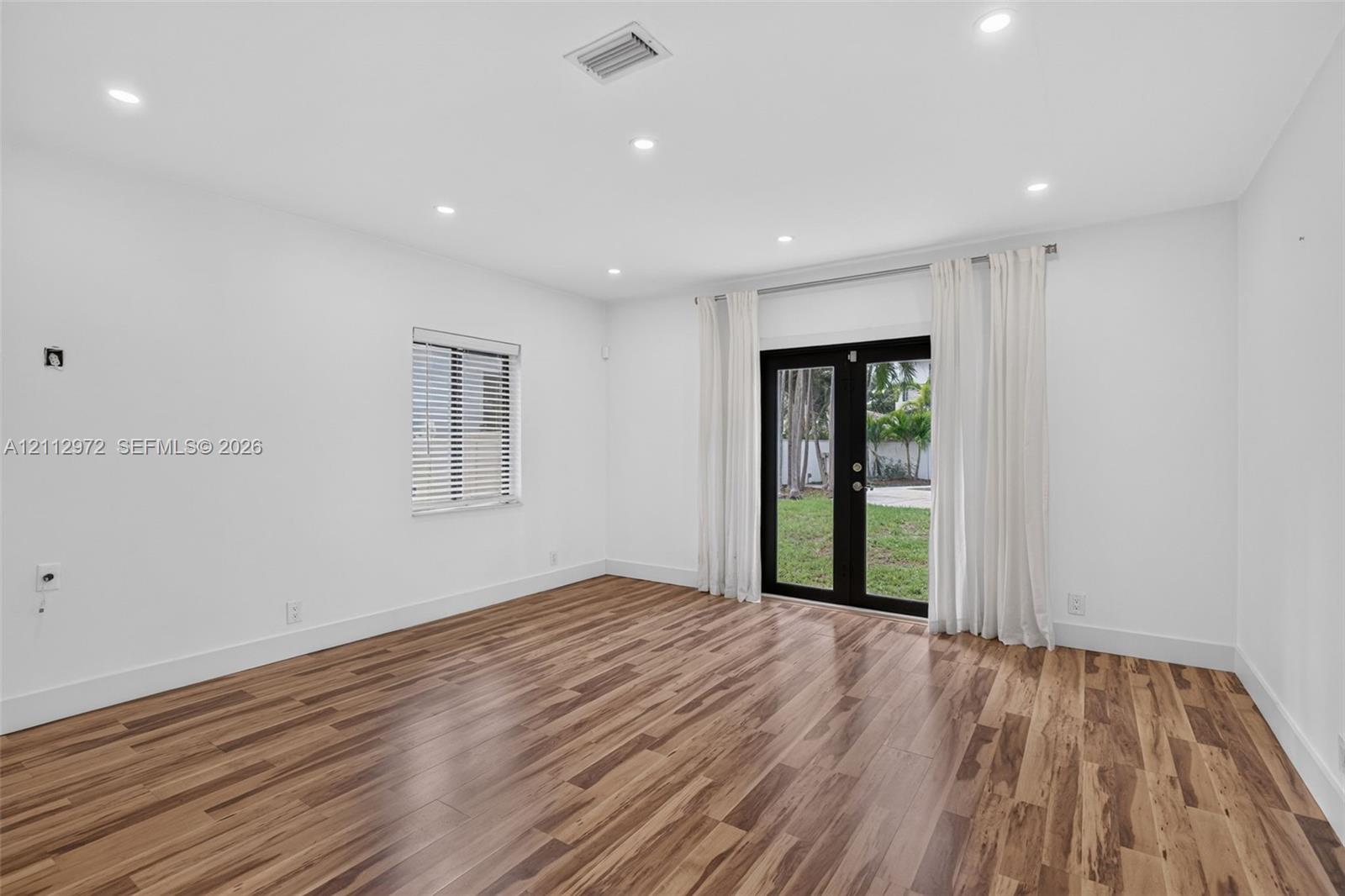 Interior space featuring wood-finish flooring, recessed lighting, and black-framed double glass doors providing an exterior perspective