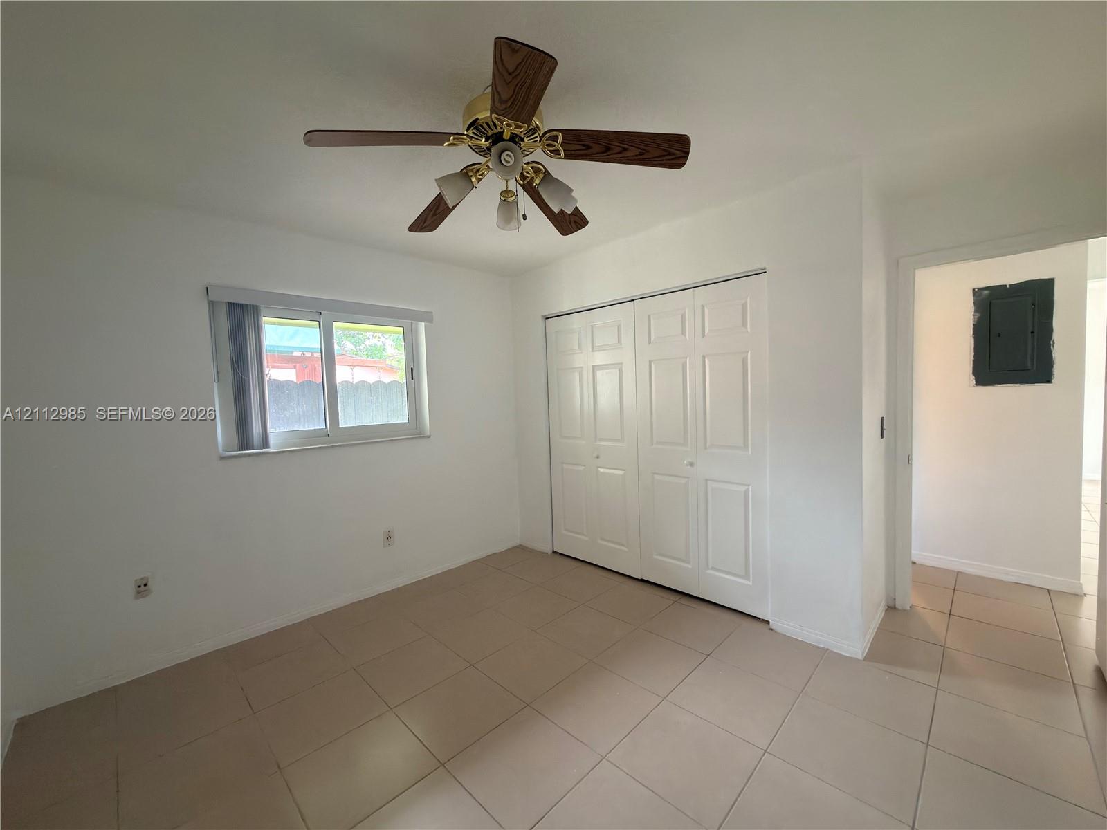 Neutral wall tones, ceramic tile flooring, ceiling fan with light fixture, and dual-panel closet doors