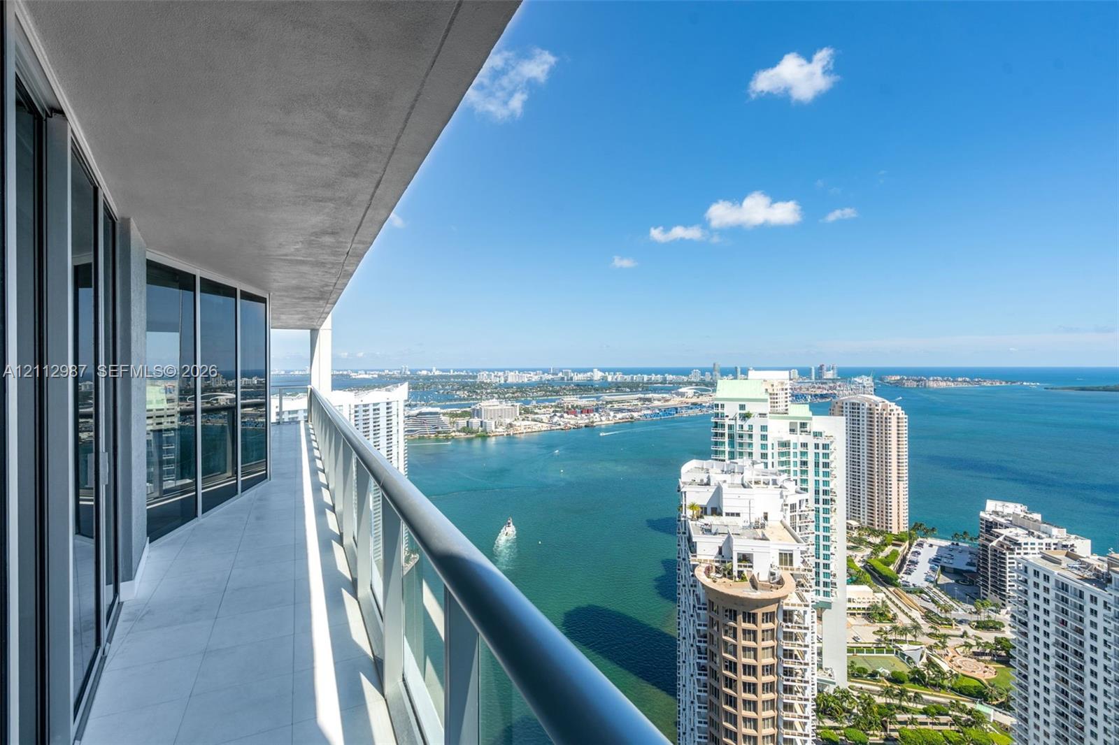 Covered balcony featuring tile flooring and a glass panel railing