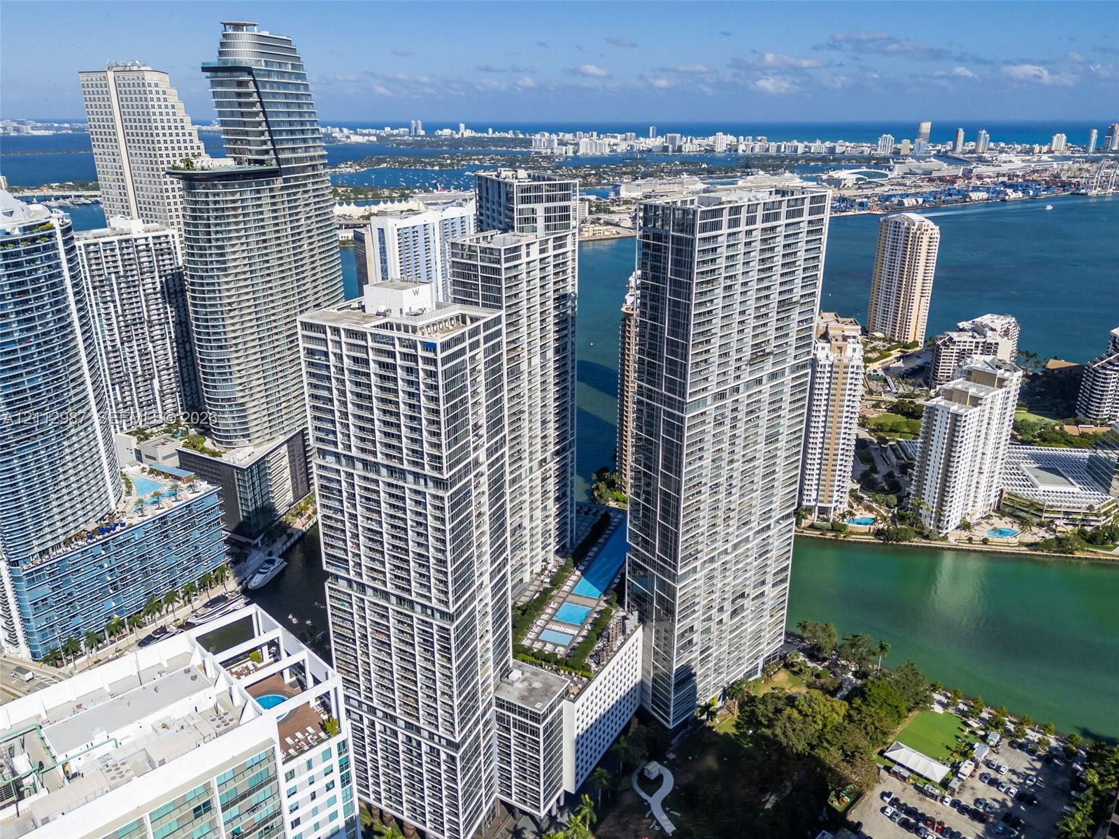 High-rise residential architecture featuring glass-facade towers, an elevated podium terrace with a swimming pool, and proximity to the waterfront