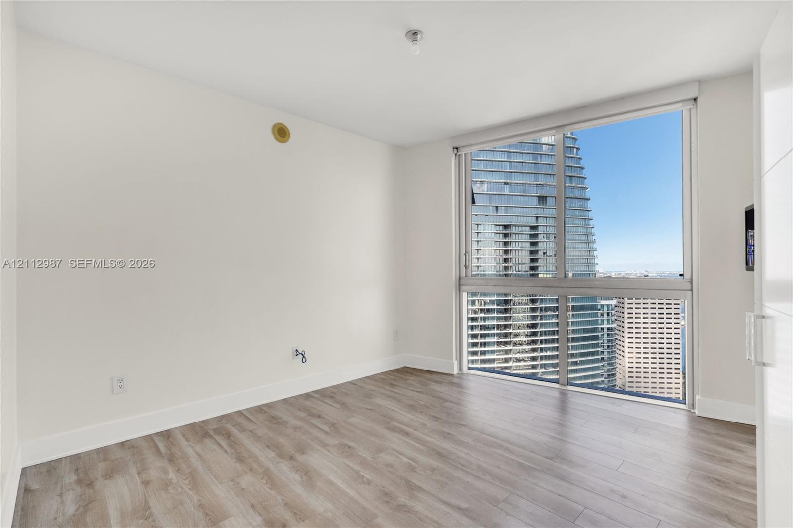 Floor-to-ceiling windows, wood-finish flooring, and white walls