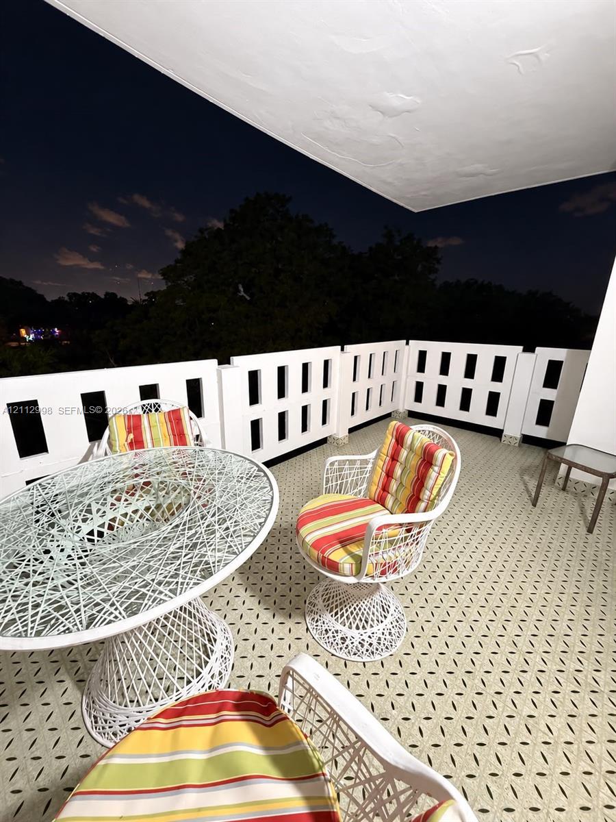 Covered balcony featuring white geometric balustrading and patterned tile flooring