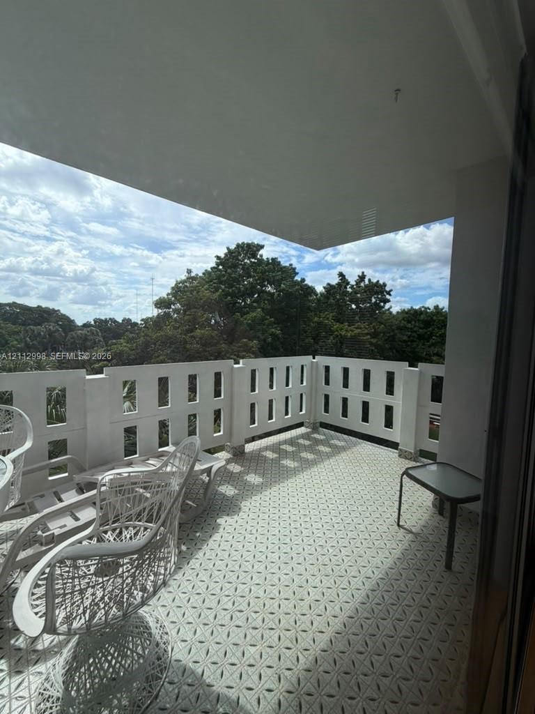 Covered balcony featuring geometric patterned tile flooring and a decorative concrete balustrade