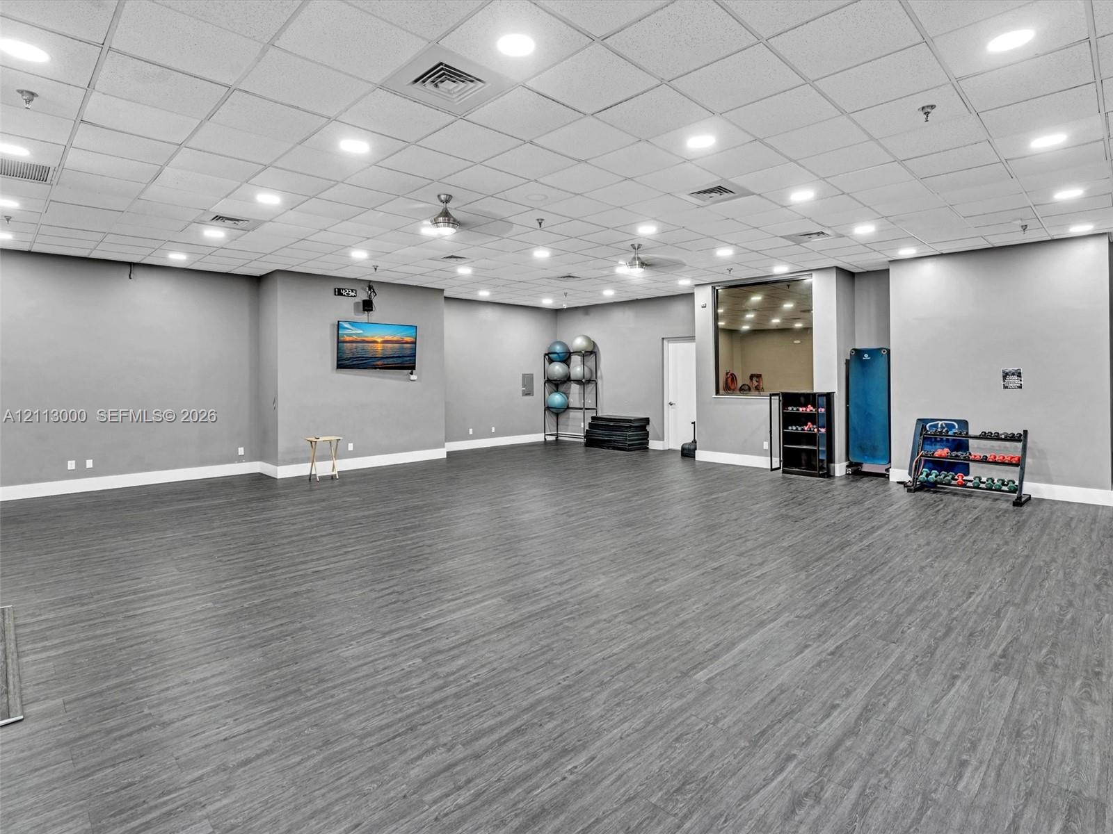 Expansive multipurpose space featuring wood-finish flooring, recessed lighting, drop ceiling, and integrated ceiling fans
