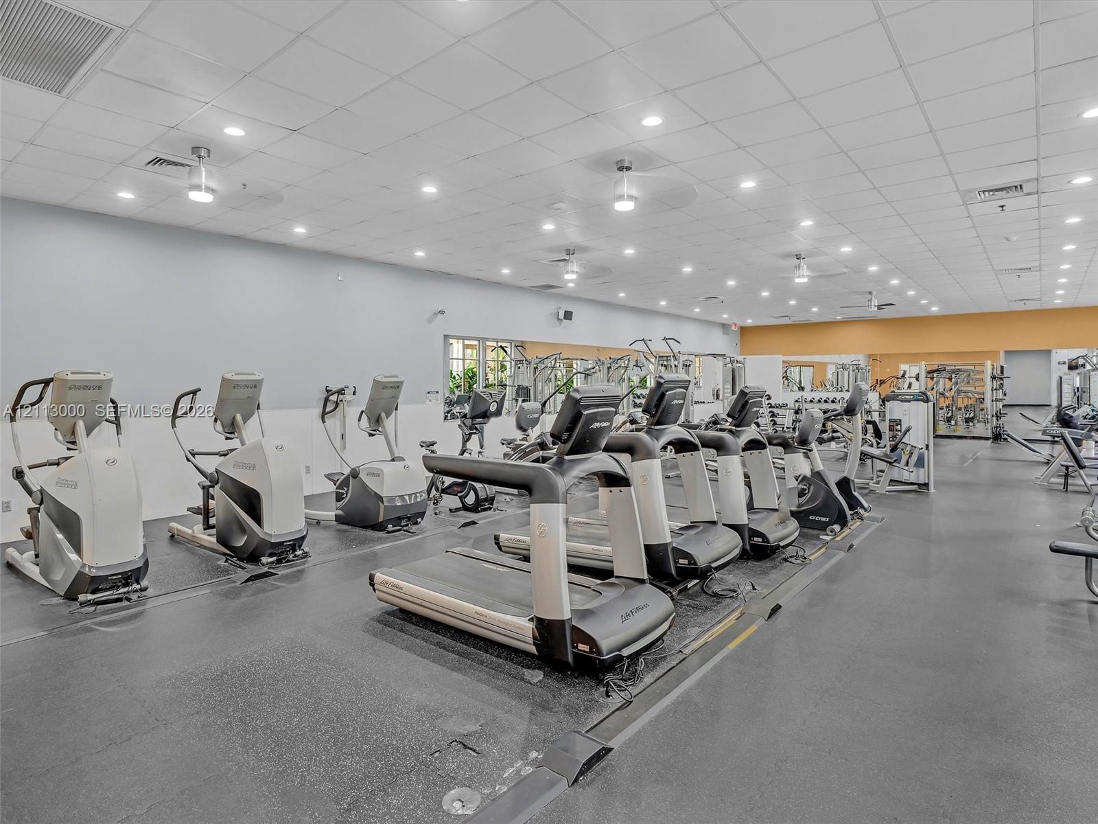 Fitness center featuring high-contrast rubber flooring, recessed ceiling lighting, and wall-to-wall mirrors