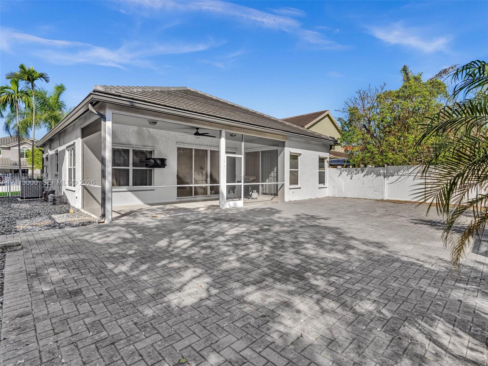 Covered screened patio featuring a paver-stone floor, ceiling fan, and stucco exterior walls