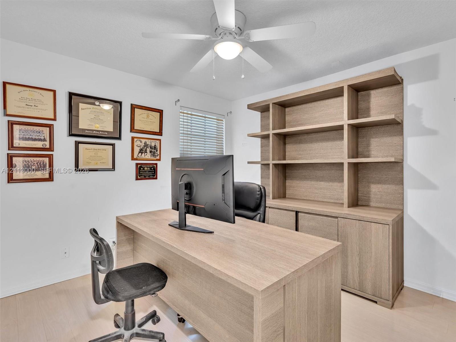 Built-in floor-to-ceiling wood-finish cabinetry, wood-finish flooring, and overhead ceiling fan with integrated light fixture