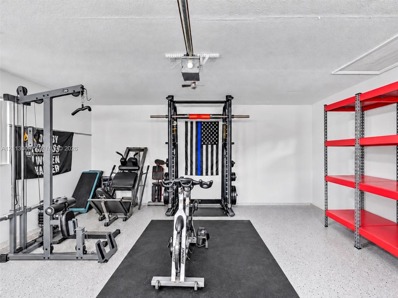 Garage space featuring an epoxy-coated floor, an automated overhead door opener, and a ceiling-mounted access hatch