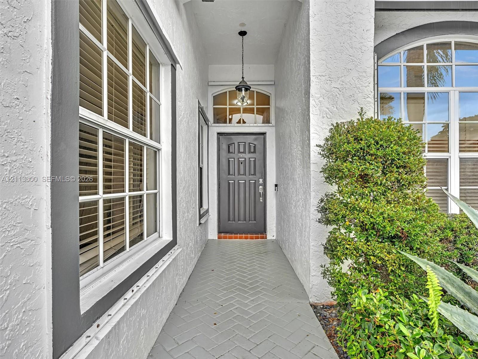 Large-format neutral tile flooring, recessed ceiling lighting, central ceiling fan, and expansive sliding glass doors