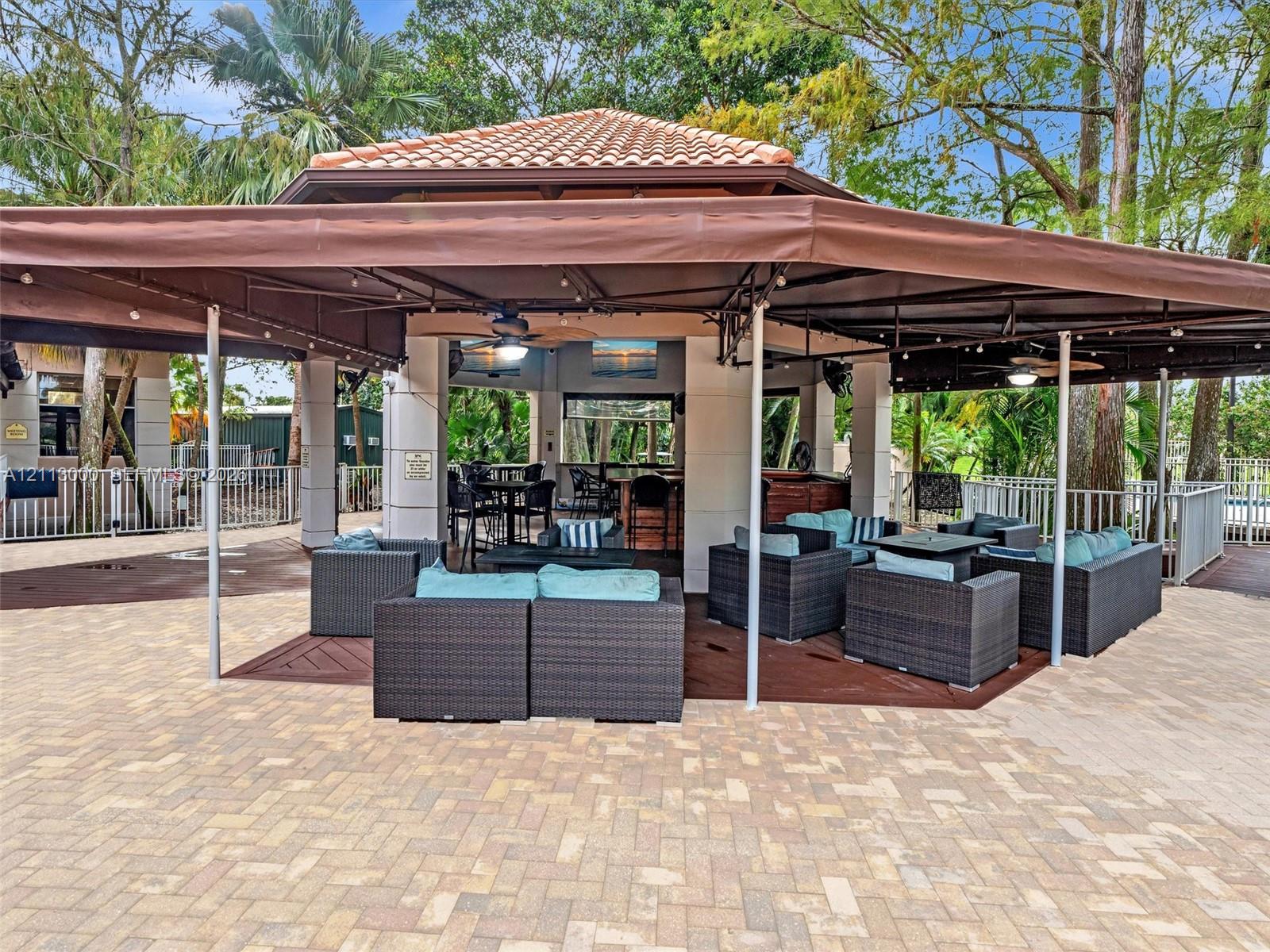 Outdoor pavilion featuring a terracotta-tiled roof, built-in bar, recessed ceiling lighting, overhead fans, and paved hardscaping