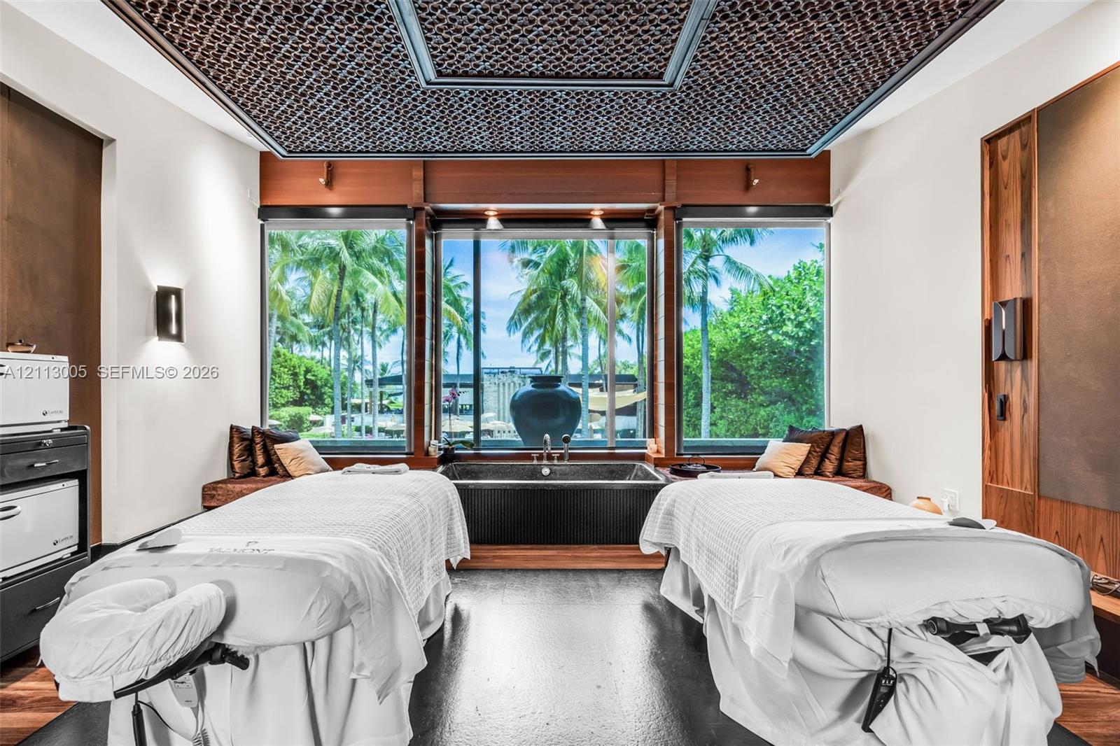Custom-designed recessed ceiling with decorative screen detailing, built-in wooden wall paneling, large-format picture windows, and integrated soaking tub with wood-finish surround