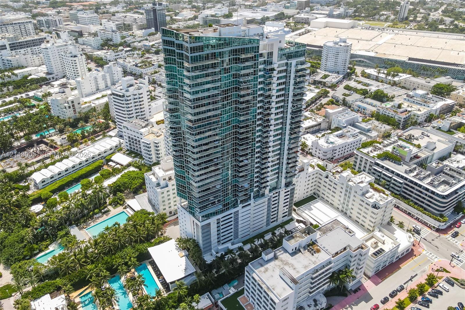 High-rise tower featuring glass facade construction, external balconies, and multi-level parking podium