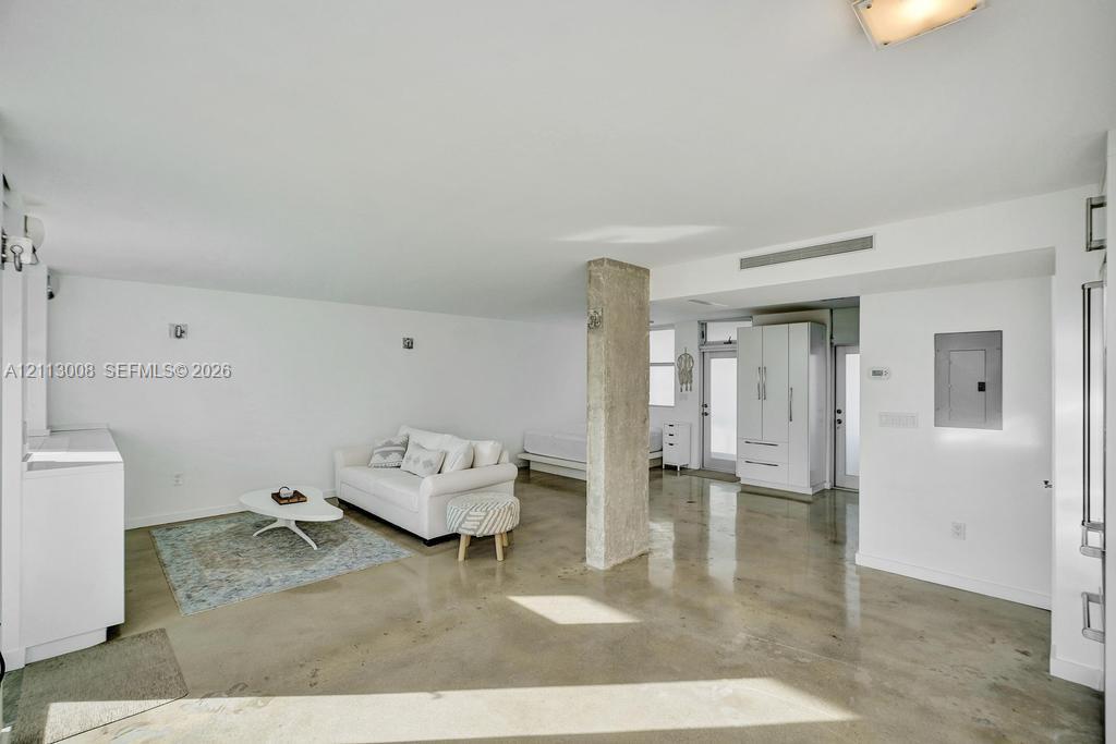 Open-concept interior featuring polished concrete flooring, an exposed structural concrete column, recessed lighting, and built-in white cabinetry
