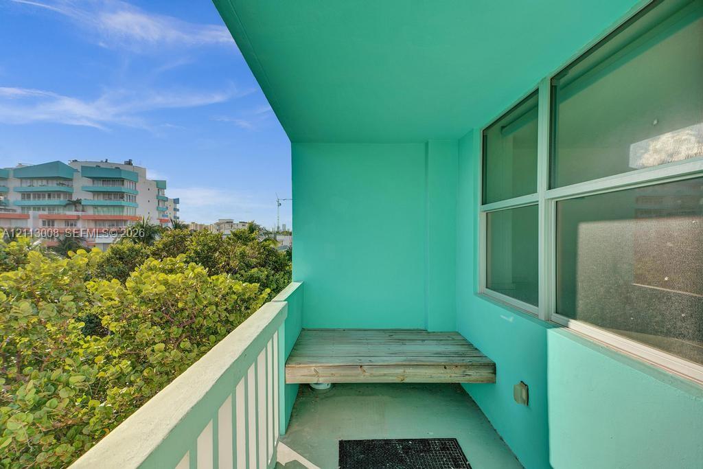 Private balcony featuring wood-finish decking, a protective railing, and exterior-grade wall finishes
