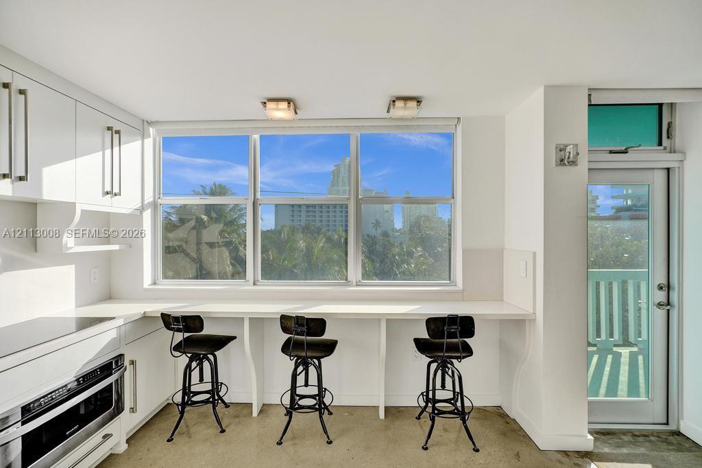Custom white cabinetry, expansive countertop workspace, triple-pane windows, and exterior door with glass insert